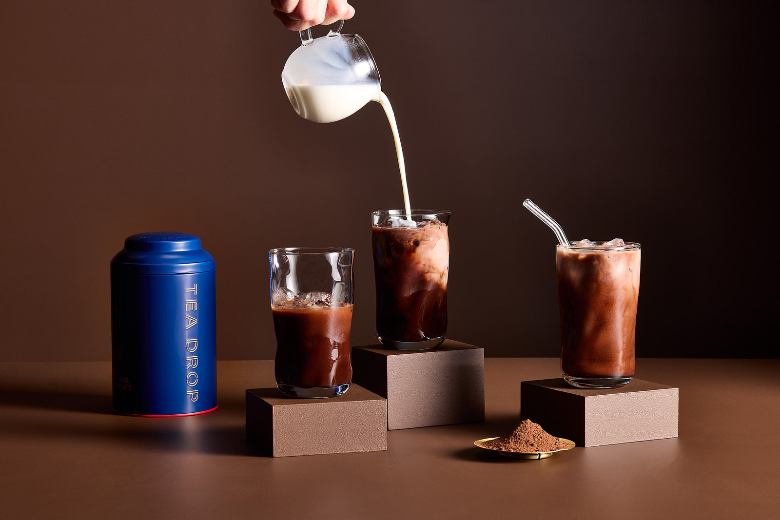Iced drinking chocolate being poured with milk over three glasses