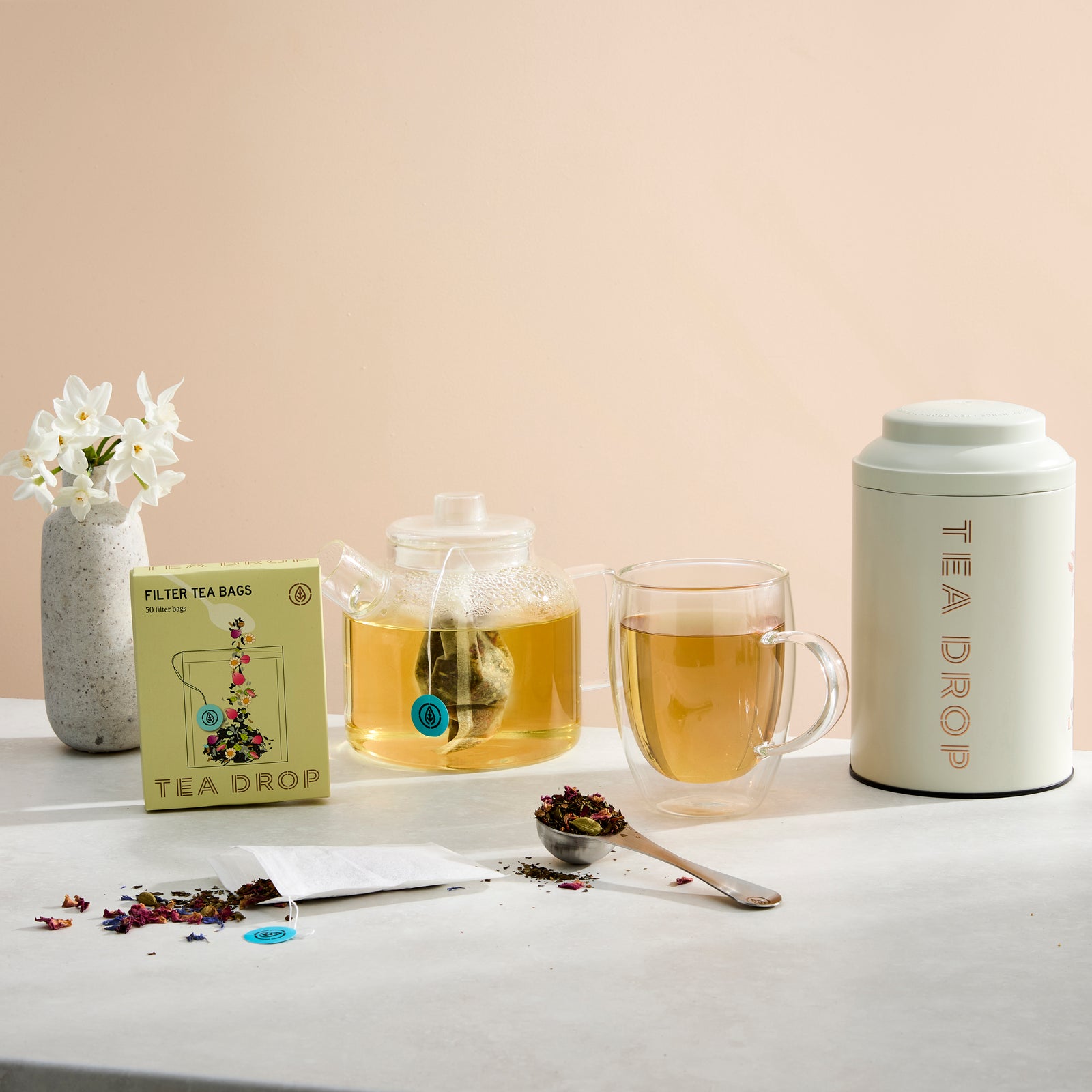 Tea Drop filter tea bags with a glass pot and cup of brewed tea
