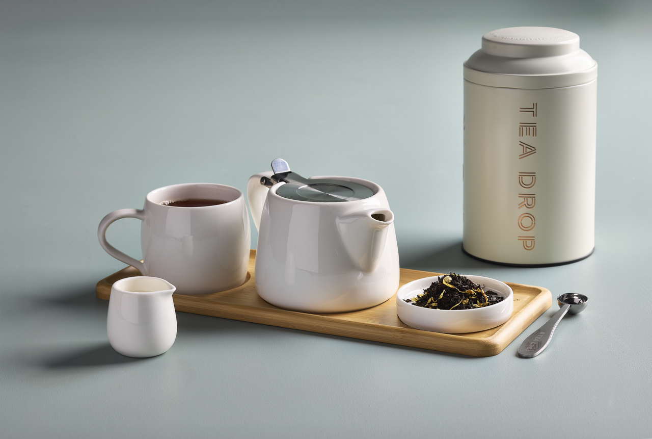 White teapot, cup and loose-leaf tea on a bamboo tray